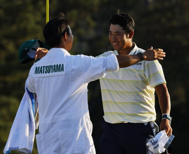 Japan's Hideki Matsuyama celebrates winning at Augusta with his caddie on the 18th green on...