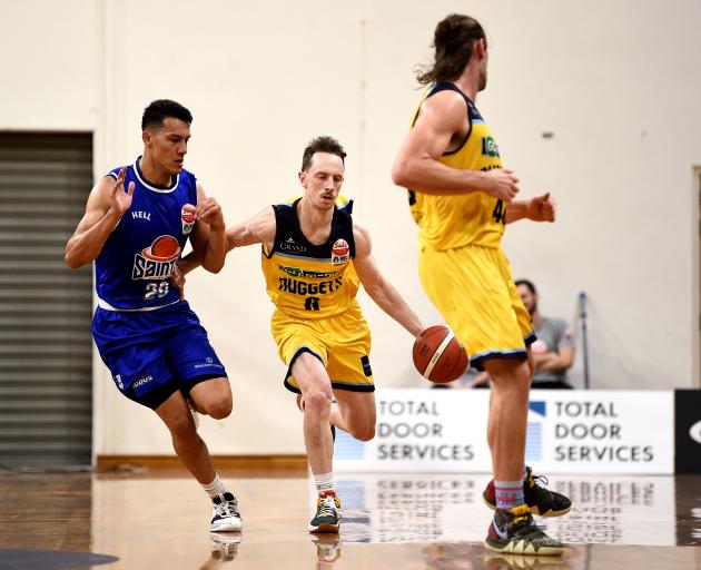 Otago Nuggets guard Darcy Knox dribbles the ball up court watched by Saints guard Kenneth Tuffin...