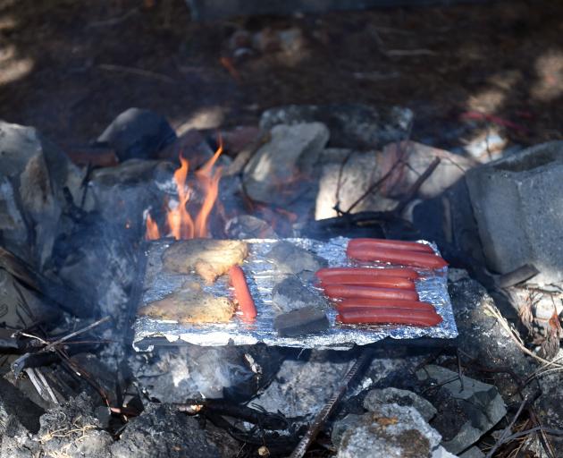 Some sausages and chicken schnitzel cook on the makeshift barbecue. PHOTO: GREGOR RICHARDSON
