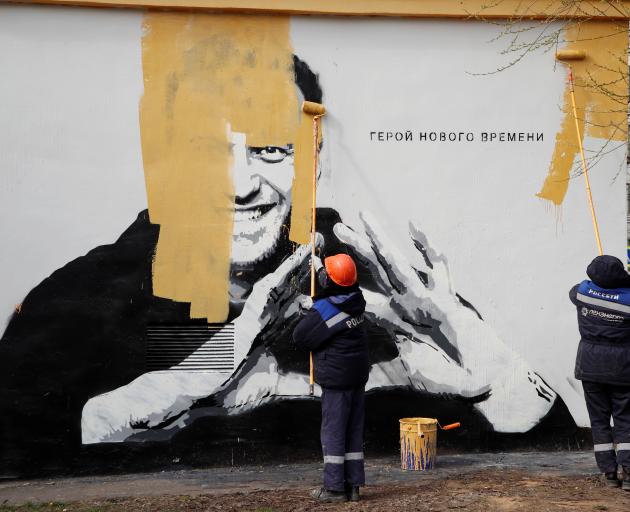 Workers paint over a graffiti depicting Alexei Navalny in Saint Petersburg. The words say: "The...