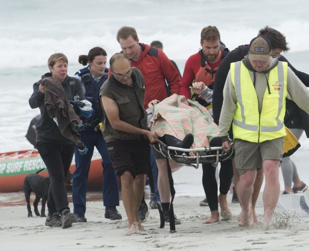 A hypothermic kayaker is taken by rescuers after being pulled from the surf at Ocean View on...