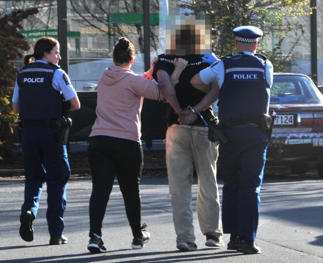 The accused is taken away by police following the incident at Countdown in central Dunedin...