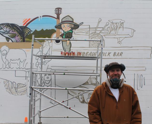 Artist Sean Duffell stands next to his mural that was commissioned under the Streets Alive...
