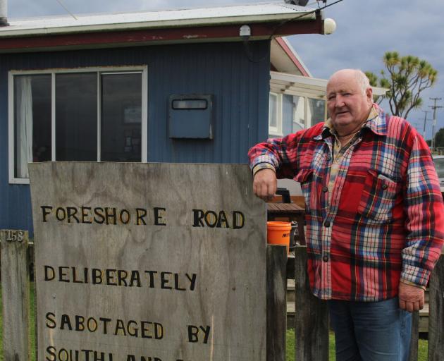 Kevin Mulqueen leans against a sign he attached to the fence of his Colac Bay home.


