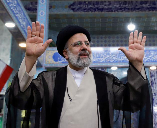 Ebrahim Raisi gestures after casting his vote during presidential elections at a polling station...