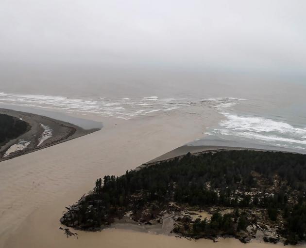Sediment-laden floodwater pours out of the mouth of the Waimakariri River at Pines Beach, north...