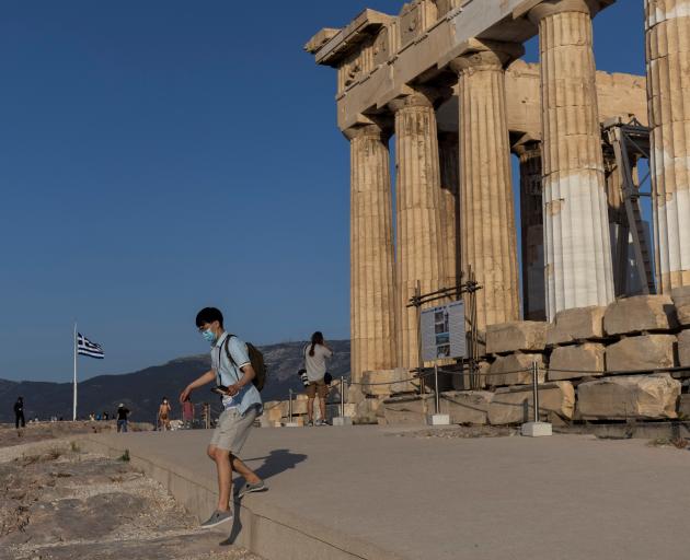 A man steps off the new cement walkway next to the Parthenon temple, built to improve access for...
