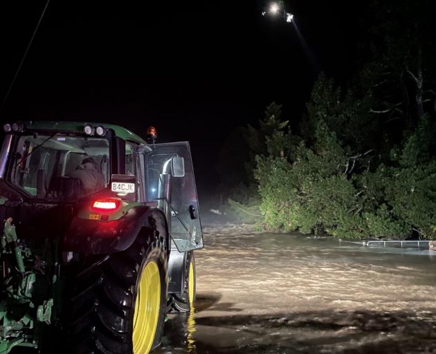 Rod May’s tractor lights up the Hawkins River and a swift water rescue crew during the first two...