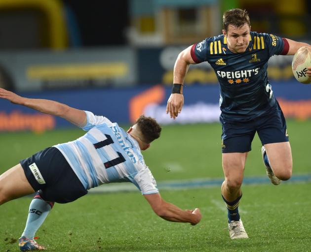 Highlanders centre Michael Collins runs past Waratahs winger Mark Nawaqanitawase at Forsyth Barr...