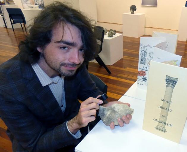 Masters student Tyler Feary studies a rock next to a book of drawings of bryozoans created by...