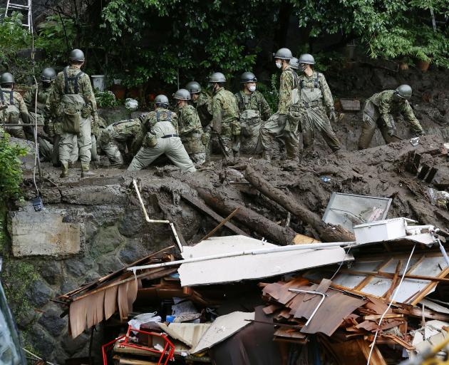 Members of Japanese Self-Defence Forces look for any survivors at a mudslide site in Atami, west...