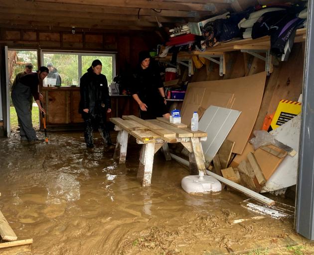 Students clean the inside of a resident’s garage after it flooded. CREDIT: OUTWARD BOUND/SUPPLIED