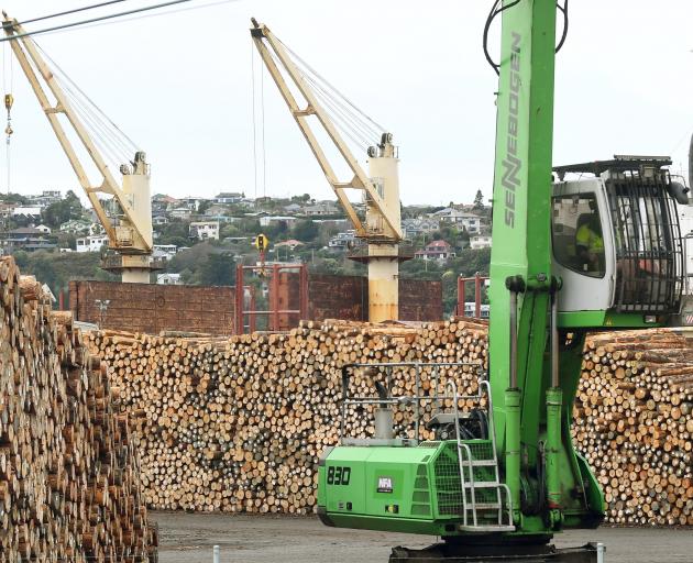 Logs are stacked in the yard at the same time as being loaded on to bulk carrier Blue Everton ...