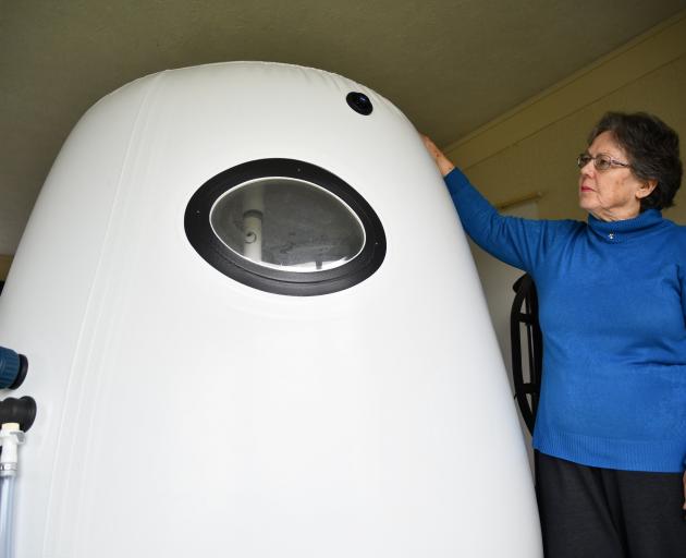 Jan Smith stands next to the personal hyperbaric chamber her husband used as therapy for motor...