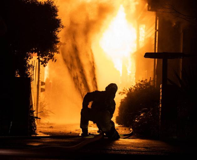 A firefighter works to douse flames at a large fire in Westport early today. Photo: NZ Herald