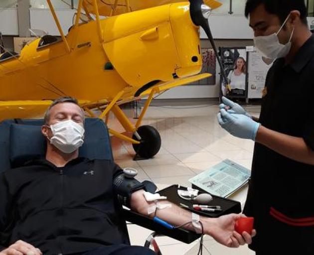 New Zealand Blood Service staff member Gian Daliva helps donor Greg Bramley to give blood in...