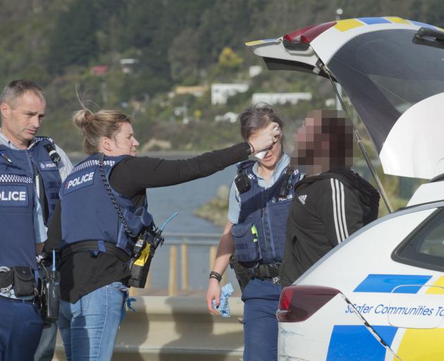 Police rinse the face of a man who was pepper-sprayed after fleeing police in Dunedin yesterday....