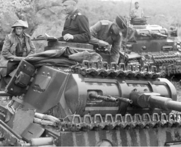 An unknown Kiwi soldier, left, sits at the back of a German tank after being captured during 1941...
