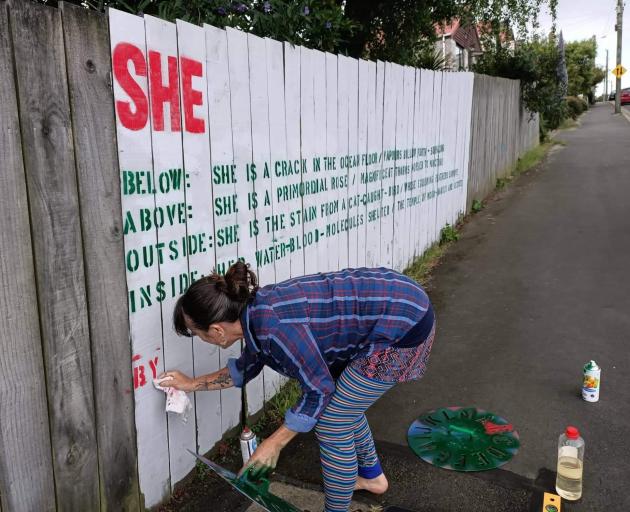 Iona Winter puts the finishing touches on her poem ‘‘Her’’ on a Port Chalmers fence. PHOTO: SUPPLIED