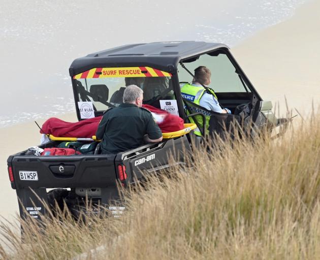 First responders help to bring an injured paddleboarder off the beach near Lawyers Head, in...