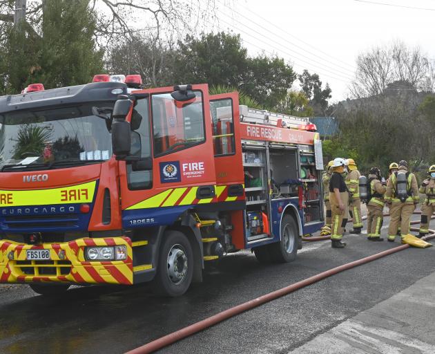 Fire and Emergency New Zealand firefighters mop up after a house fire in Warrington. PHOTO: LINDA...