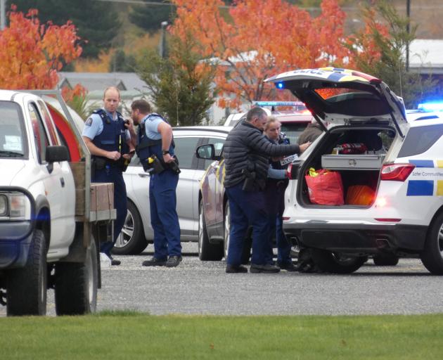 Police officers escort a 59-year-old man (obscured) wanted in relation to family harm and...