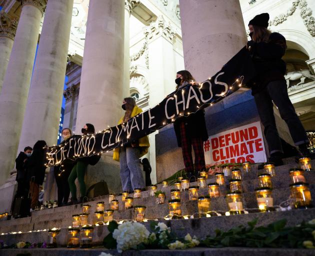 Environmental activists hold a banner as they attend a vigil near the Bank of England in London ...
