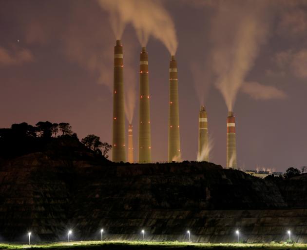 Smoke and steam billows from the coal-fired power plant owned by Indonesia Power, next to an area...