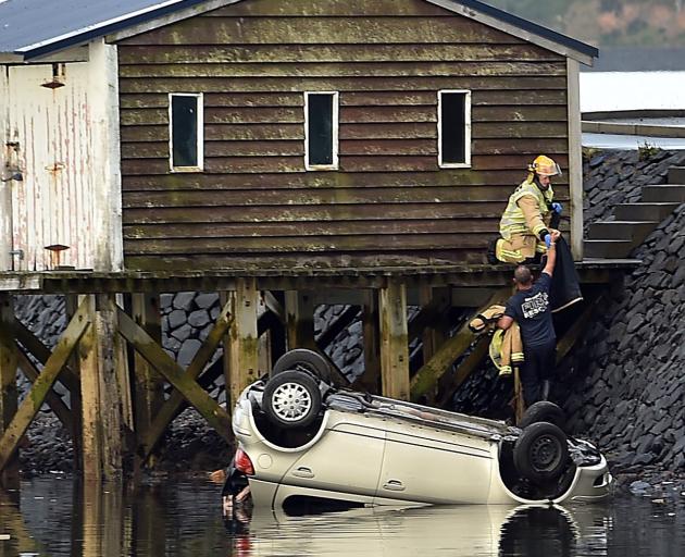 Emergency services attend to a vehicle in the harbour near Rosehill Rd and Macandrew Bay on...