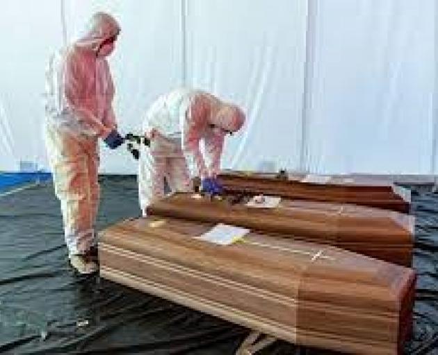 A Civil Protection member rests a flower on the coffin of a coronavirus victim in Bergamo, Italy....