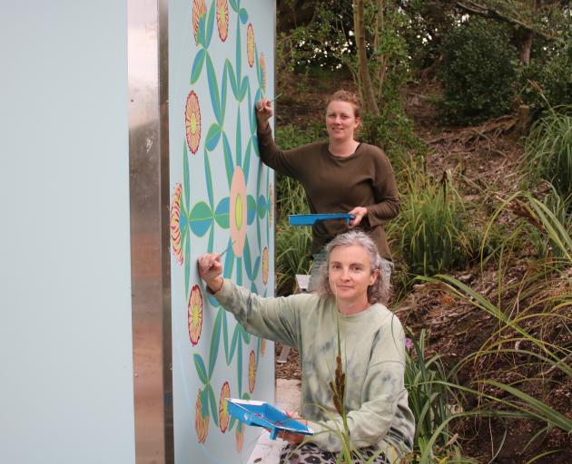 Natalie Carpenter (front) and Tracey Vickers paint a mandala on a wall of the Campbells Bay...