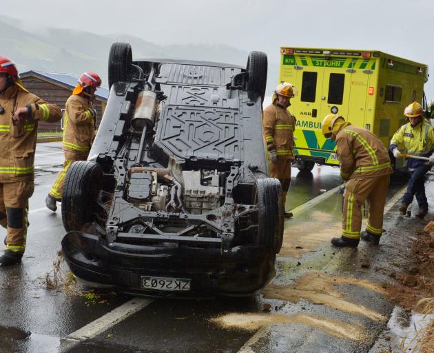 Firefighters contain leaking fluids from a car that rolled in Portobello Rd on November 27, 2015....