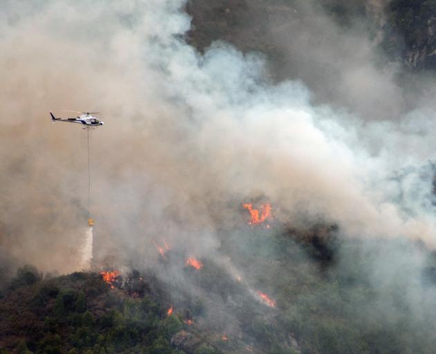 A helicopter empties its bucket in the fight against a fire on Glendhu Hill yesterday. PHOTO:...