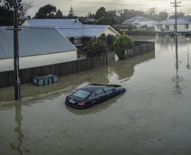 A partly-submerged car outside flooded Westport houses in July. Photo: Supplied/NZ Defence Force
