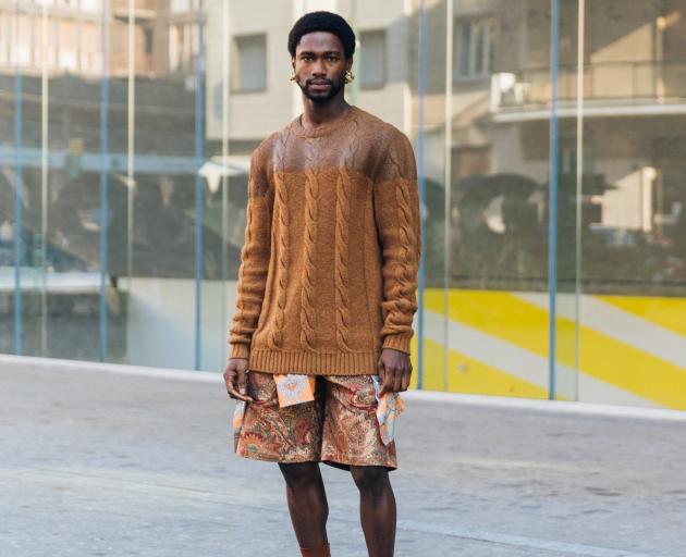 A fashion week guest wears a chunky cable knit sweater in a brown gradient, paired with paisley...