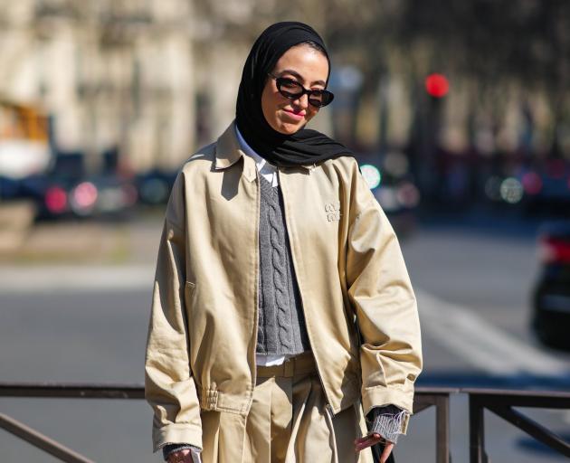 A Paris Fashion Week attendee effortlessly layers cable knit over a full pleated skirt and under...