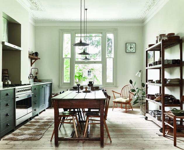 A bank of cupboards and long table lead the eye to a large sash window. A tonal palette of dark...
