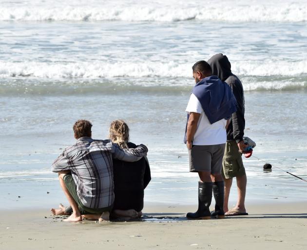 People comfort each other at a beach at Aramoana on Saturday, where surfer James Civil died....