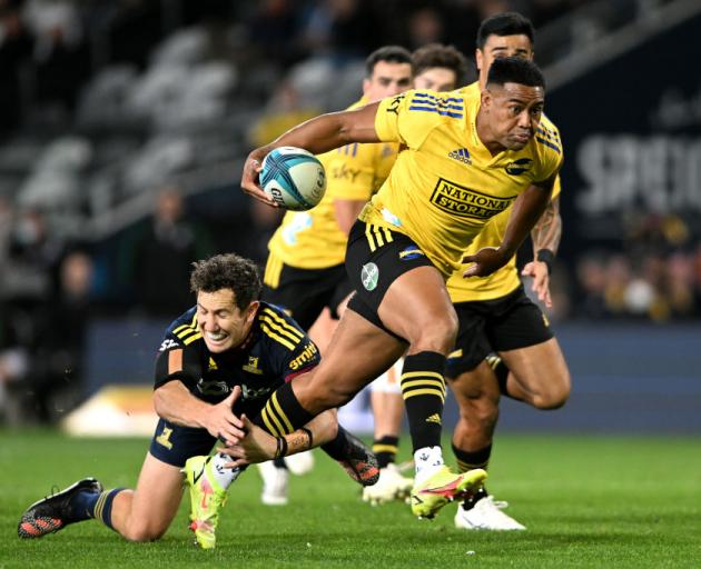 Hurricanes winger Julian Savea attempts to evade the tackle of Highlanders first five Marty Banks...