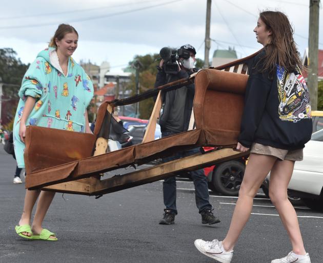 Students Rhianna Parry (19, left) and Kyla Brindle (19) dispose of a burned-out sofa in Castle St.