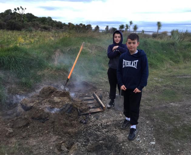 Helping their grandfather Bob put out a tyre fire at Whalers Bay are (From left) Saul (9), and Sabin (11) Sutherland. PHOTO: SUPPLIED