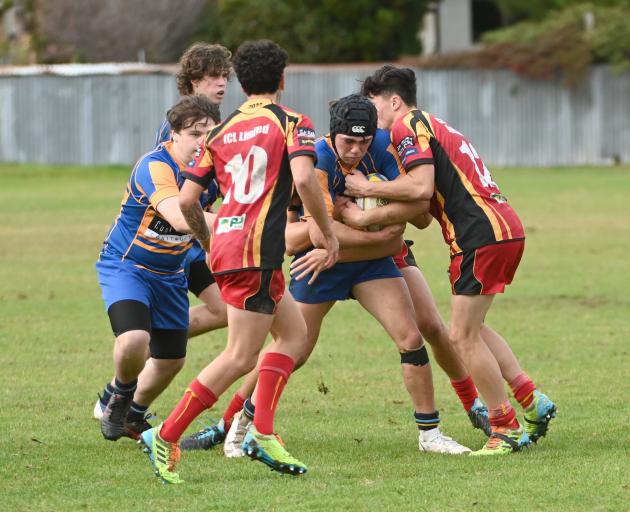 Taieri player Josh Munro is tackled by Dunstan defenders Raf Love (left) and Finn O’Brien during...