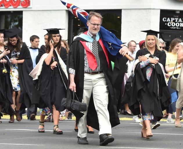 Caroline Freeman College warden Chris Addington, carrying a flag, together with students and...