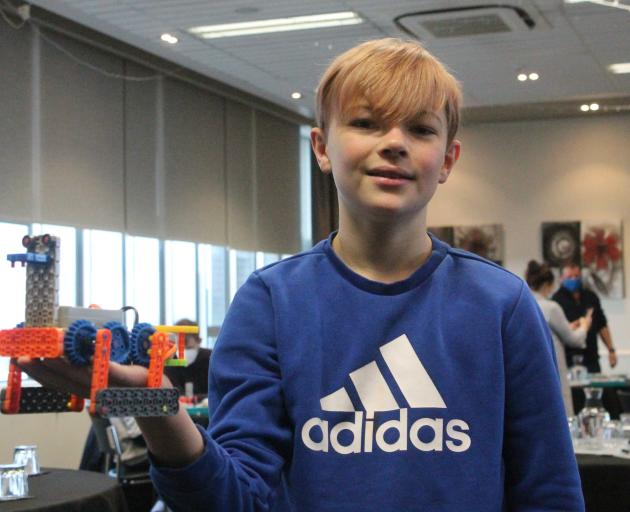 Ryan Howden proudly shows the robot he built as part of the workshop ‘‘Build your own robot! —...