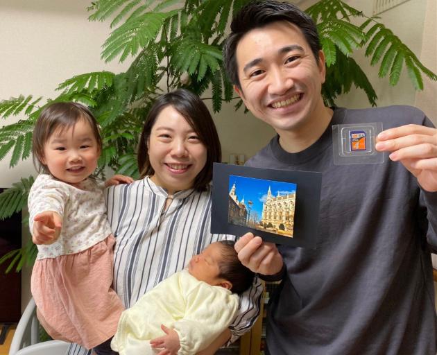 Akina Tominaga holds her daughters Itoha (3 weeks) and Fumika (2), while husband Shunya Tominaga...