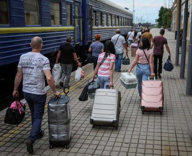 Ukrainian refugees prepare to board a train as they evacuate from war-affected areas of eastern...