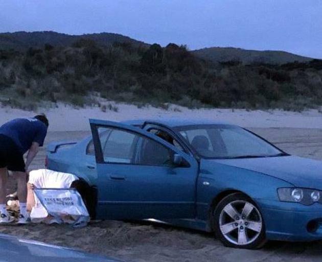 A vehicle stuck in the sand at dusk after racing and doing doughnuts at Cannibal Bay, October,...