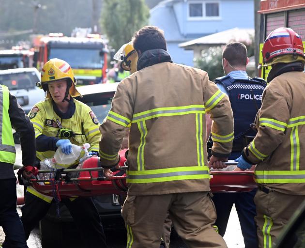 Fire crews stretcher a man away from a house fire in Peter St, Caversham, yesterday. PHOTO: CRAIG...