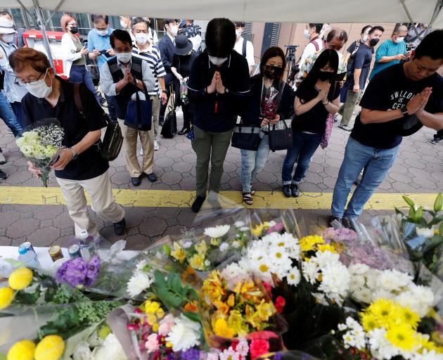 People pray next to flowers laid at the site where late former Japanese Prime Minister Shinzo Abe...