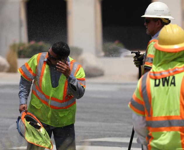 A Desert Water Agency worker is sprayed to cool him down in Palm Springs, California. Photo:...